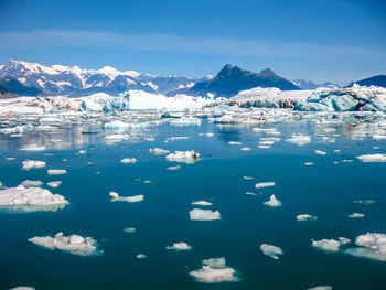 Scenic view of lake and snowcapped mountains against blue sky