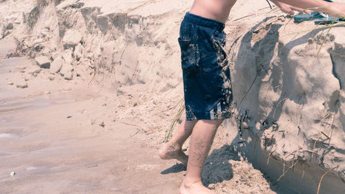 Low section of man standing on beach