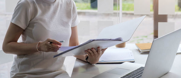 Midsection of man using mobile phone while sitting on table