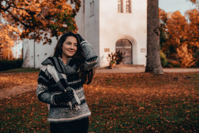 Portrait of smiling woman standing in park during autumn