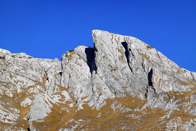 Low angle view of rock formations against clear blue sky