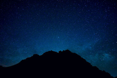 Low angle view of silhouette mountain against sky at night