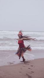 Rear view of woman standing at beach against clear sky