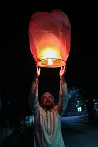 Person holding  illuminated paper lantern at night on diwali 