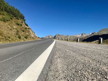 Surface level of empty road against clear blue sky
