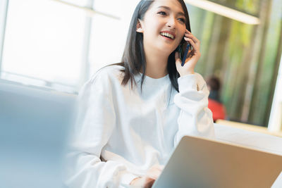 Smiling young woman using mobile phone