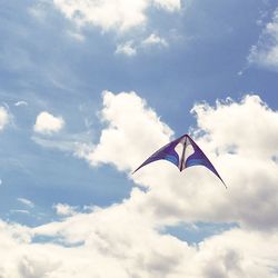 Low angle view of kite against cloudy sky