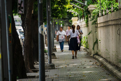 Rear view of people walking on footpath