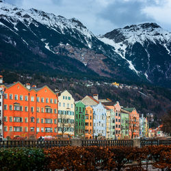 Houses by mountain against sky during winter