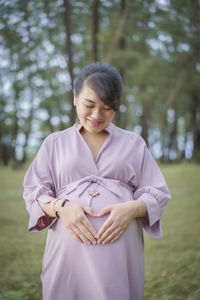 Beautiful pregnant woman standing in park