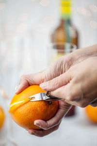 Cropped image of hands peeling orange fruit