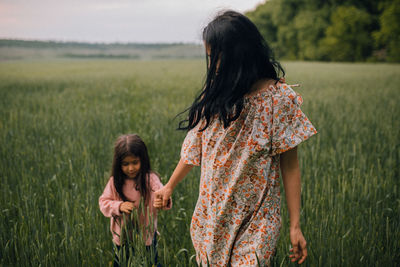 Happy mother walking with child in field at dusk