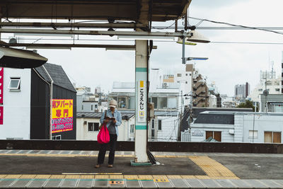 Rear view of woman walking on street against buildings in city