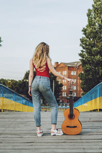 Full length rear view of woman playing guitar