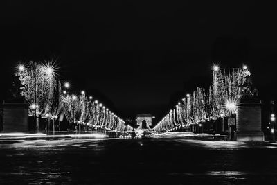 Firework display over illuminated city against sky at night