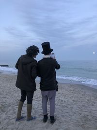 Rear view of friends standing on beach