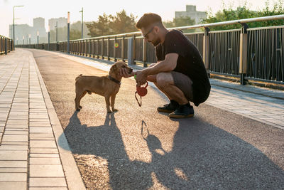 Young man is playing with his dog on empty street in the morning.