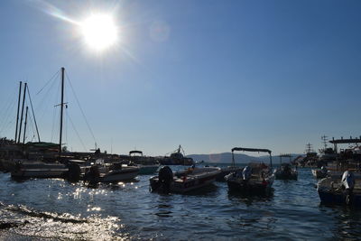 Sailboats moored in sea against sky on sunny day