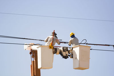 Low angle view of worker working against sky