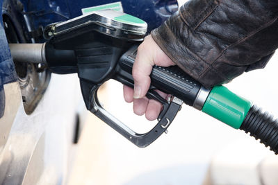 Cropped hand of woman refueling car at gas station