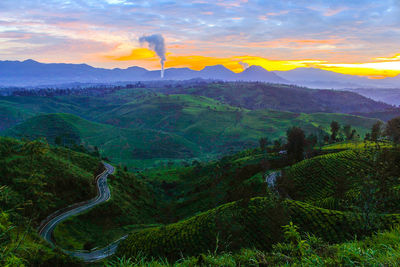 Scenic view of green landscape against sky during sunset