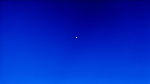 Low angle view of moon against clear blue sky