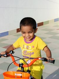 Smiling boy riding bicycle on footpath