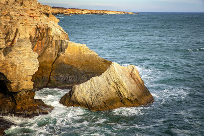 Rock formation in sea against sky