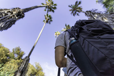 Low angle view of man with backpack standing against clear sky