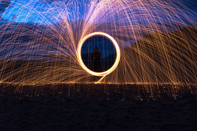 Close-up of person spinning wire wool at night