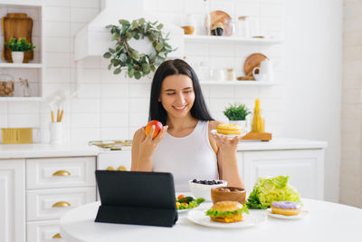 Happy woman nutritionist holds an online lesson or conference in the kitchen on the topic of healthy