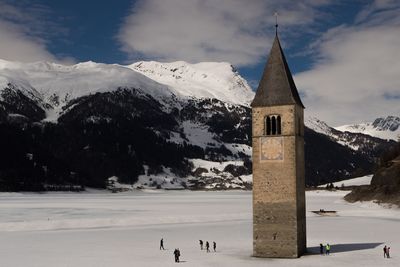 People outside bell tower on snow covered field