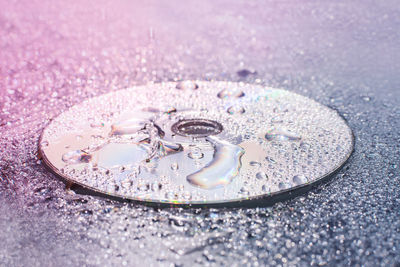 Close-up of raindrops compact disc on surface