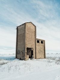 Old building on field against sky during winter