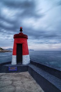 Lighthouse by sea against sky