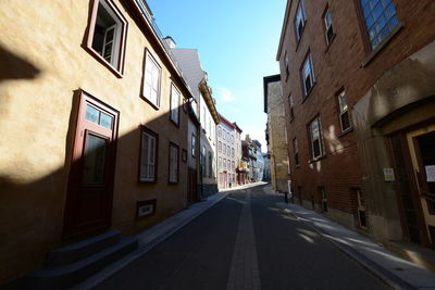 Empty road amidst buildings against sky