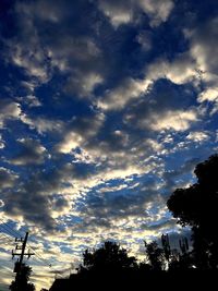 Low angle view of silhouette trees against cloudy sky