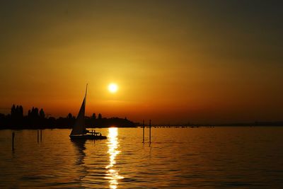 Silhouette sailboats in sea against sky during sunset