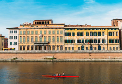 Building by river against sky in city