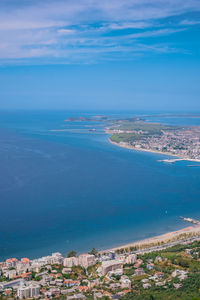 Aerial view of townscape by sea against blue sky
