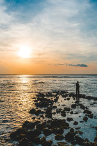 Silhouette people on beach against sky during sunset