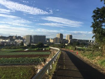 Railroad tracks by buildings in city against sky