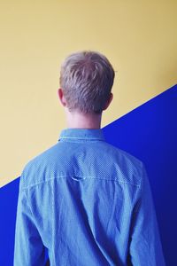 Young man against wall against blue background
