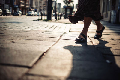 Low section view of woman walking on sidewalk