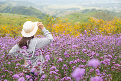 Midsection of woman with flowers in field