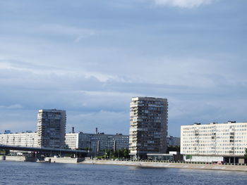 Buildings by river against sky in city