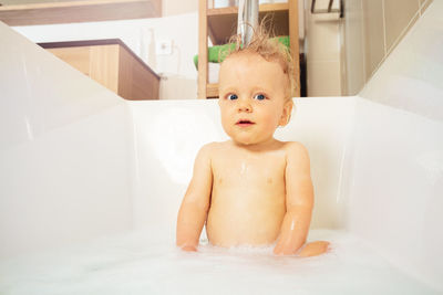 Portrait of shirtless boy washing hair in bathroom