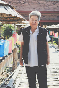 Portrait of smiling senior woman standing on footpath