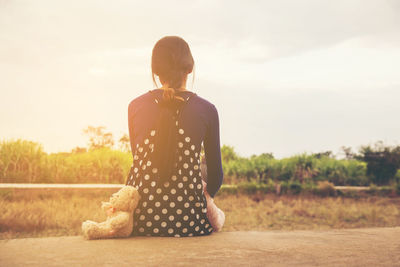 Rear view of woman standing on field against sky