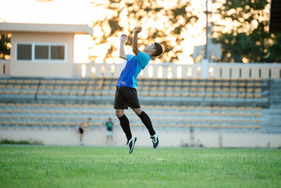 Side view of man playing soccer on field